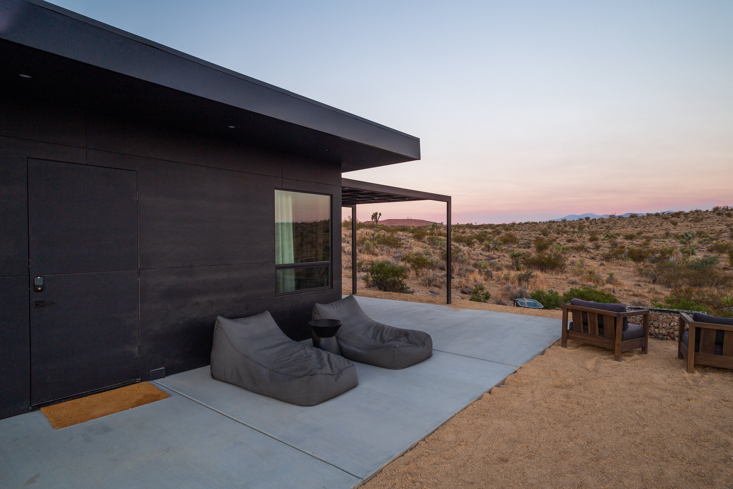 Pause House PM's dark facade and beanbags at pink dusk