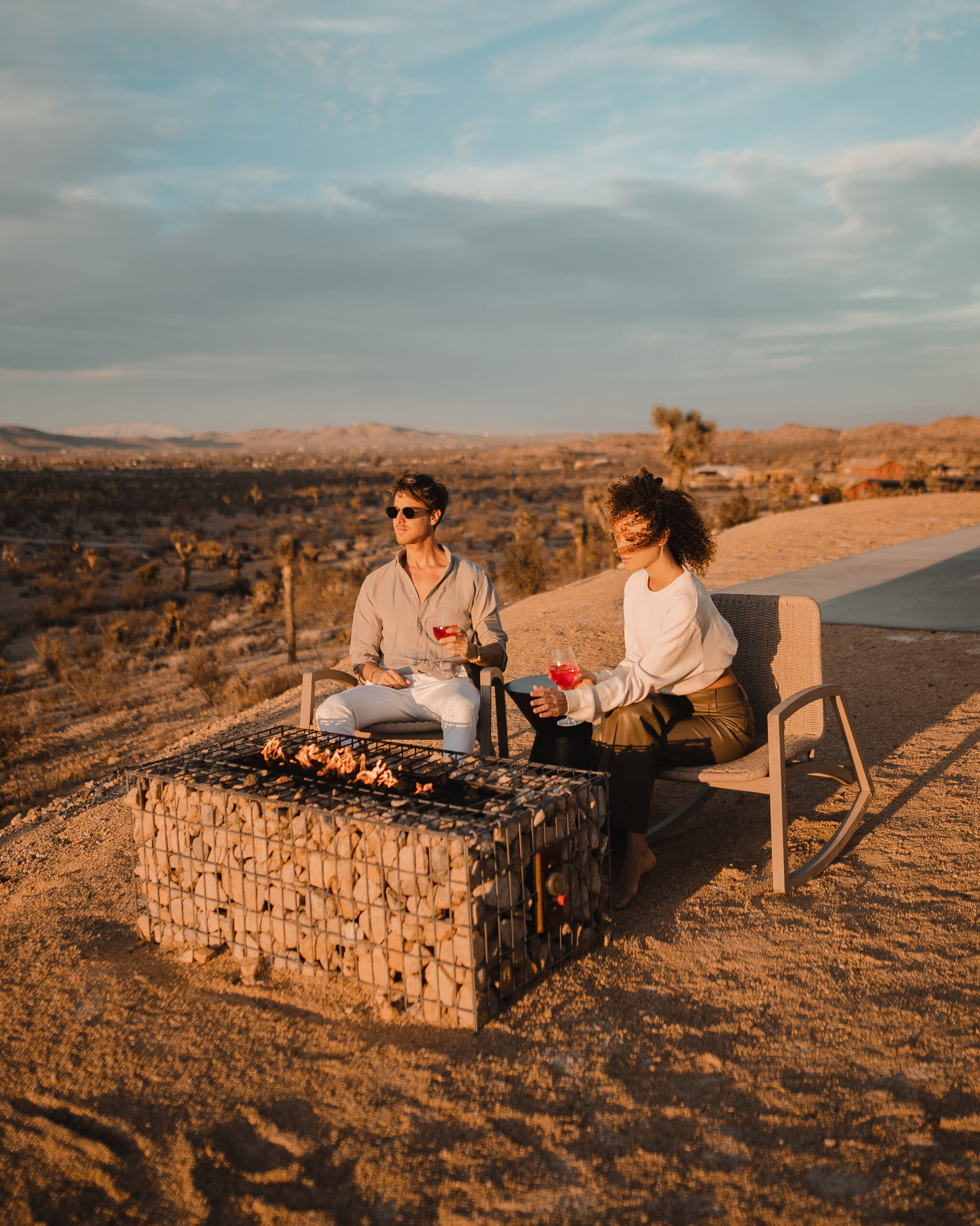 Couple beside the gabion fire pit at sunset